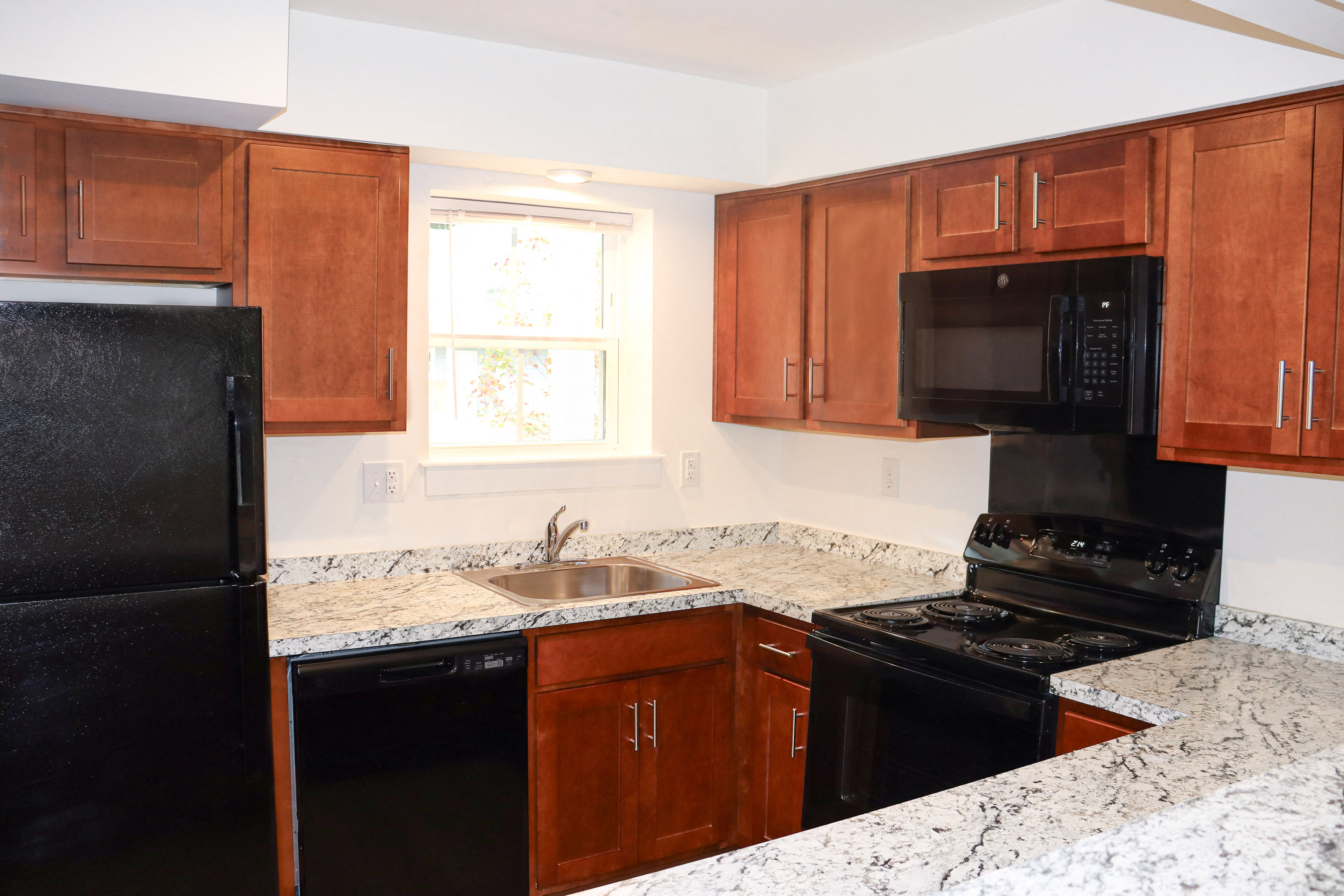an empty kitchen with granite counter tops and black appliances